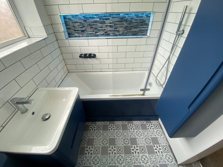 Bathroom with navy vanity units, illuminated mosaic niche and patterned floor tiles