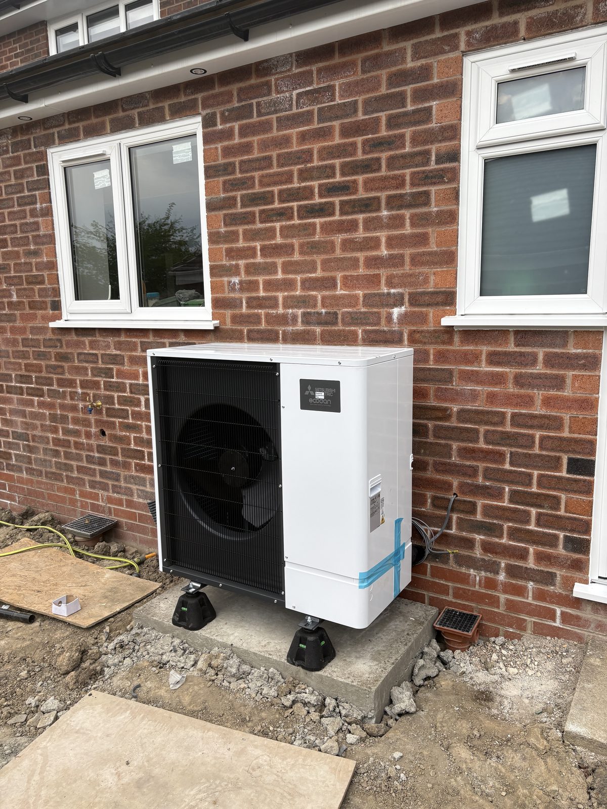 Air source heat pump outdoor unit being installed on a new concrete base