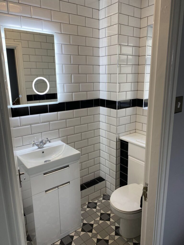 Monochrome bathroom with white metro tiles, black border and patterned floor tiles