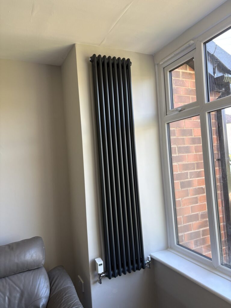 Tall vertical anthracite column radiator fitted with a smart thermostatic radiator valve